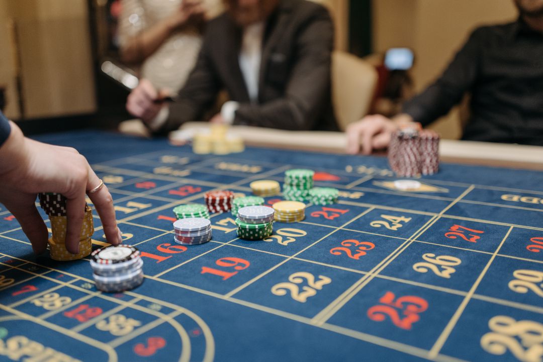 Chip kasino diletakkan di atas meja roulette oleh tangan pemain