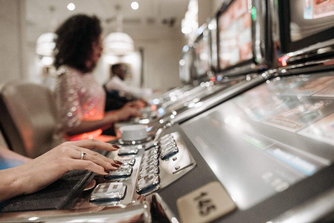 Tangan pemain menekan tombol mesin slot di kasino